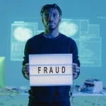 man holding light box with word fraud displayed